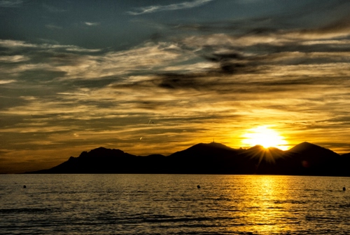 Immagine con tramonto, mare, nuvole, sole, riflesso, acqua, montagne, isola, alba, cielo, controluce